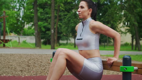 A-female-athlete-performs-reverse-exercises-on-a-bench-in-a-Park-in-slow-motion.-Beautiful-woman-playing-sports-in-the-Park